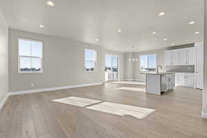 Unfurnished living room featuring sink, light hardwood / wood-style flooring, and a chandelier