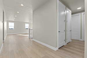 Hallway with a textured ceiling and light wood-type flooring