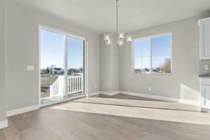 Unfurnished dining area featuring a chandelier and light hardwood / wood-style flooring