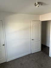 Unfurnished room featuring dark carpet