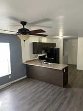 Kitchen featuring a textured ceiling, washing machine and dryer, dark wood-type flooring, and black appliances