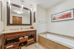 Bathroom with vanity and tiled bath