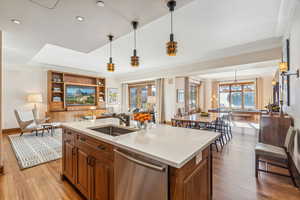 Kitchen with dishwasher, sink, plenty of natural light, an island with sink, and light wood-type flooring