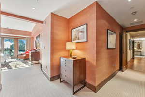 Corridor with beam ceiling, light colored carpet, and french doors