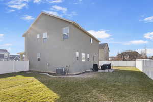 Rear view of property featuring a yard, a patio, and central air condition unit