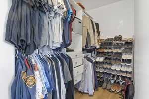 Walk in closet with light hardwood / wood-style flooring