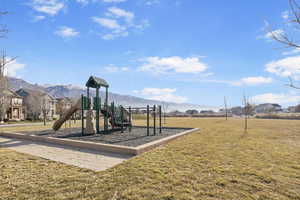 View of jungle gym with a mountain view and a yard