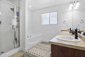 Bathroom featuring tile patterned flooring, vanity, and plus walk in shower