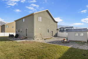 Rear view of house featuring a lawn, a mountain view, a fire pit, a storage shed, and a patio