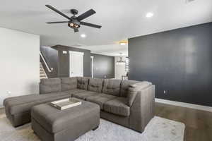 Living room with ceiling fan with notable chandelier and light wood-type flooring