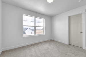 Spare room with baseboards, carpet, visible vents, and a textured ceiling