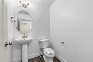 Bathroom featuring a sink, toilet, baseboards, and wood finished floors