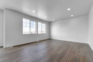 Spare room with recessed lighting, baseboards, and wood-type flooring