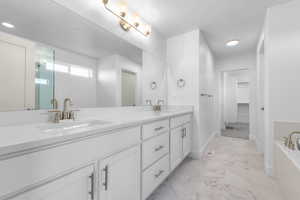 Bathroom with double vanity, marble finish floor, a textured ceiling, and a sink