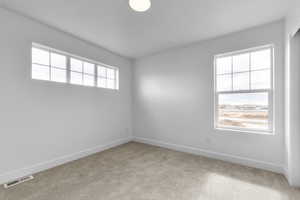 Carpeted spare room featuring baseboards and visible vents