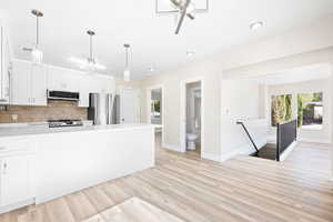 Kitchen with white cabinets, light wood-type flooring, and appliances with stainless steel finishes