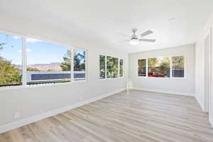 Unfurnished sunroom featuring plenty of natural light, ceiling fan, and a mountain view