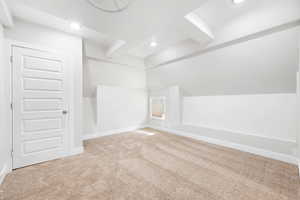 Additional living space featuring light colored carpet and vaulted ceiling