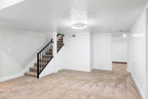 Basement featuring light carpet and a textured ceiling