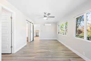 Hallway featuring an AC wall unit, a barn door, and light hardwood / wood-style floors