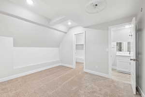 Additional living space featuring light colored carpet and vaulted ceiling