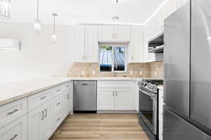 Kitchen featuring white cabinetry, sink, light hardwood / wood-style flooring, and appliances with stainless steel finishes