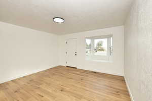 Foyer entrance with light hardwood / wood-style flooring and a textured ceiling