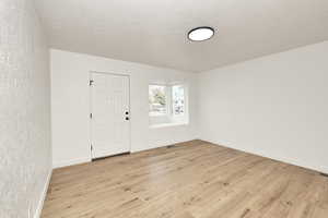 Entrance foyer with a textured ceiling and light hardwood / wood-style flooring