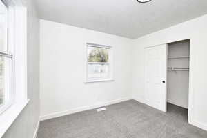 Unfurnished bedroom featuring carpet, a textured ceiling, and a closet