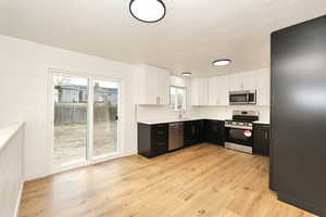 Kitchen featuring light hardwood / wood-style flooring, stainless steel appliances, white cabinetry, and sink