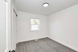 Unfurnished bedroom with dark carpet and a textured ceiling