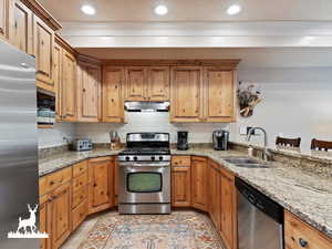 Kitchen featuring light stone countertops, sink, a kitchen breakfast bar, decorative backsplash, and appliances with stainless steel finishes