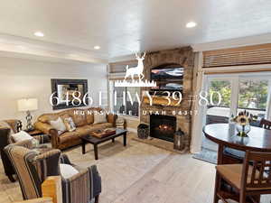 Living room featuring a fireplace, a textured ceiling, light hardwood / wood-style floors, and ornamental molding