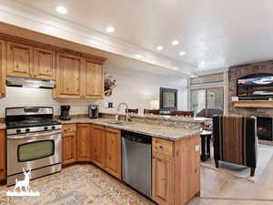 Kitchen featuring kitchen peninsula, tasteful backsplash, light stone counters, stainless steel appliances, and sink