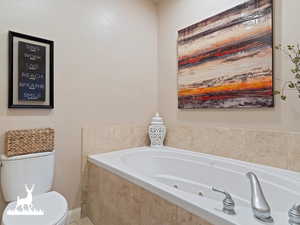 Bathroom with a relaxing tiled tub and toilet