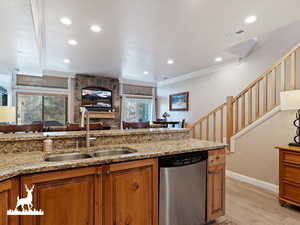 Kitchen featuring sink, light hardwood / wood-style flooring, stainless steel dishwasher, ornamental molding, and light stone counters