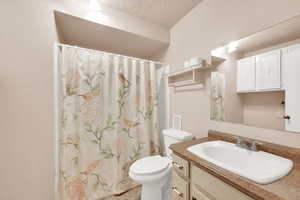 Bathroom featuring vanity, a textured ceiling, and toilet