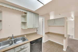 Kitchen with dishwasher, gray cabinets, light tile patterned floors, and sink