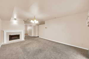 Unfurnished living room featuring a tile fireplace, carpet floors, and a chandelier