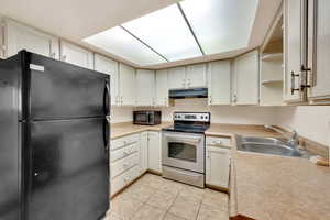 Kitchen featuring cream cabinetry, light tile patterned floors, stainless steel appliances, and sink