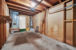 Basement with strapped water heater, heating unit, and a workshop area