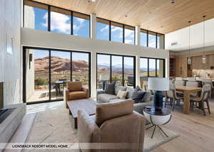 Living room featuring a mountain view, a healthy amount of sunlight, light wood-type flooring, and a high ceiling