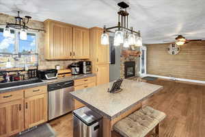 Kitchen with a fireplace, ceiling fan, dark wood-type flooring, dishwasher, and a kitchen island