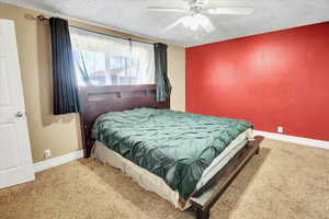 Carpeted bedroom featuring ceiling fan and a textured ceiling