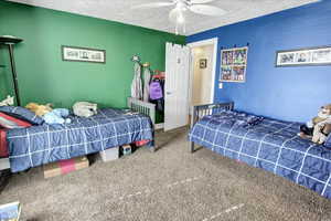 Bedroom featuring carpet flooring, a textured ceiling, and ceiling fan