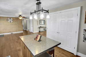 Kitchen featuring ceiling fan, a center island, dark hardwood / wood-style floors, wood walls, and pendant lighting