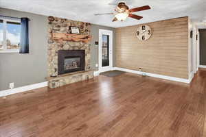 Unfurnished living room featuring a textured ceiling, ceiling fan, a fireplace, and hardwood / wood-style flooring