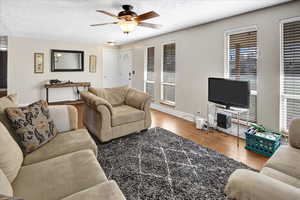 Living room featuring hardwood / wood-style floors, ceiling fan, and a textured ceiling