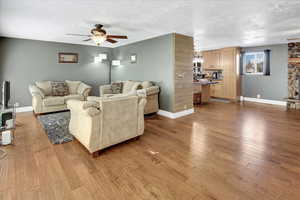 Living room with hardwood / wood-style floors, a textured ceiling, and ceiling fan