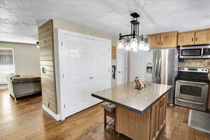 Kitchen with a center island, hanging light fixtures, ceiling fan, dark hardwood / wood-style floors, and appliances with stainless steel finishes